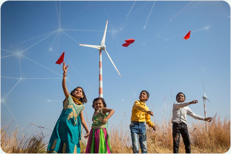Children flying paper birds near a wind turbine